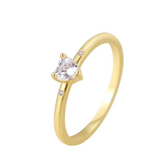 Bague dorée or 18K pour femme, ornée d’un zircon blanc en forme de cœur accompagné de deux pierres latérales scintillantes, au style romantique, minimaliste et raffiné, parfaite comme bague de promesse ou cadeau d’amour.