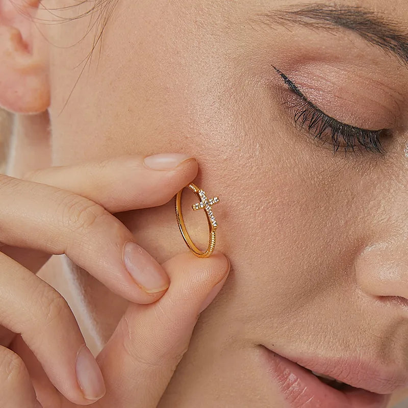 Bague dorée or 18K pour femme, ornée d’une croix sertie de zircons blancs sur un anneau torsadé fin, au style minimaliste et spirituel, symbole de foi et d’élégance intemporelle.