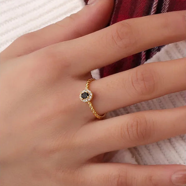 Bague dorée or 18K pour femme, ornée d’une pierre noire facettée entourée de zircons blancs sur un anneau torsadé raffiné, au style chic, féminin et intemporel, alliant contraste et élégance moderne.