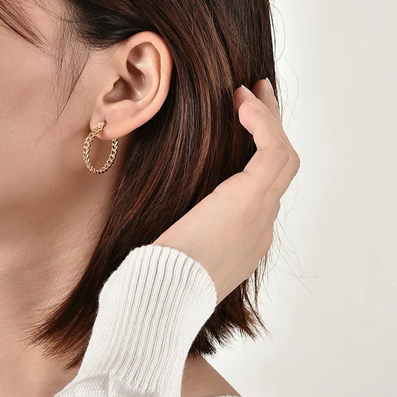 Boucles d’oreilles créoles dorées pour femme en plaqué or, au design torsadé effet tressé en relief. Bijou chic et intemporel au style moderne et vintage, lumineux et confortable, parfait pour un look citadin ou sophistiqué.