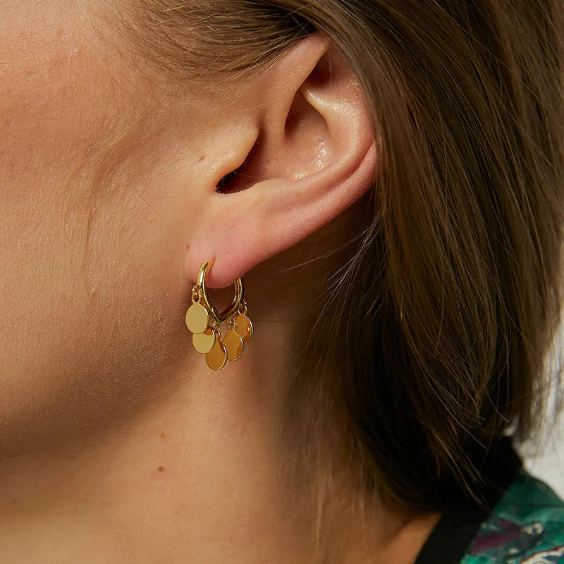 Boucles d’oreilles pendantes dorées pour femme en plaqué or, au design goutte ajourée ornée de cinq pastilles ovales mobiles. Bijou lumineux et fluide au style bohème-chic et solaire, parfait pour un look estival élégant et naturel