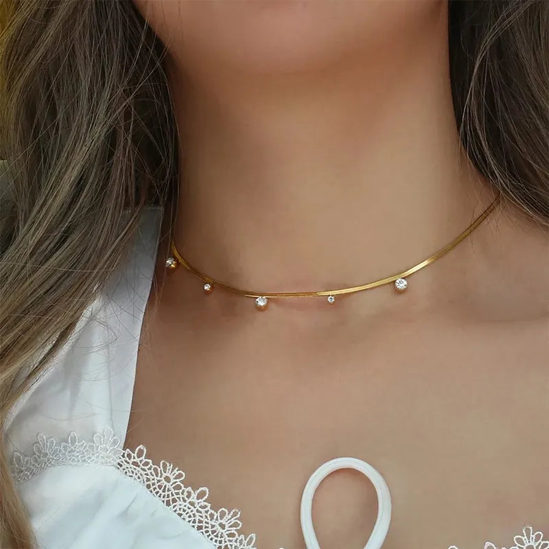 Collier en acier inoxydable doré pour femme, orné de zircons sertis sur une chaîne serpent lisse et brillante, alliant élégance moderne et finesse intemporelle.