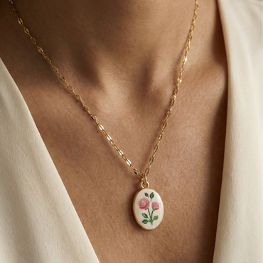 Collier doré en acier inoxydable avec pendentif ovale émaillé roses sur fond blanc