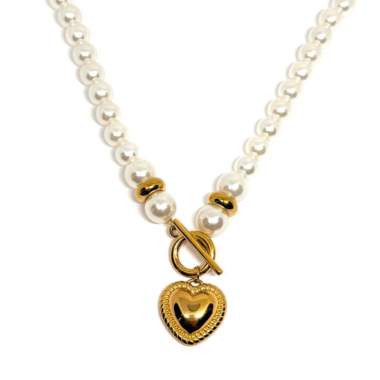 Collier pour femme composé de perles blanches nacrées et de perles dorées, orné d’un pendentif cœur bombé couleur or avec fermoir toggle à l’avant. Bijou romantique et vintage en acier inoxydable, résistant à l’eau et hypoallergénique.