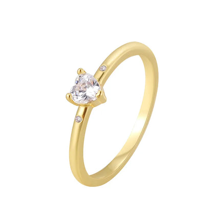 Bague dorée or 18K pour femme, ornée d’un zircon blanc en forme de cœur accompagné de deux pierres latérales scintillantes, au style romantique, minimaliste et raffiné, parfaite comme bague de promesse ou cadeau d’amour.