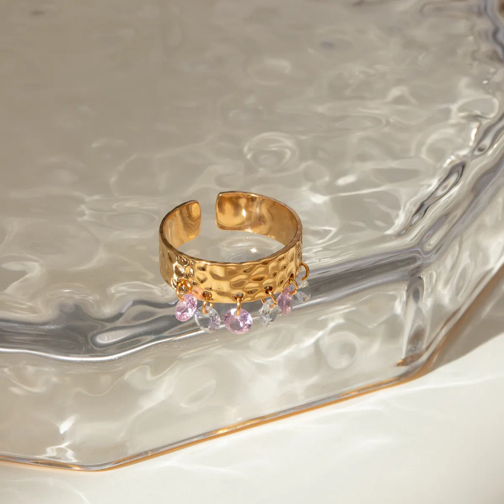 Affirmez votre style avec cette bague dorée ajourée à l’architecture moderne, composée de cinq anneaux texturés reliés entre eux, ponctués de petites sphères dorées et ornée d’une pierre noire centrale. Un bijou à la fois audacieux et élégant, parfait pour sublimer vos tenues avec caractère.