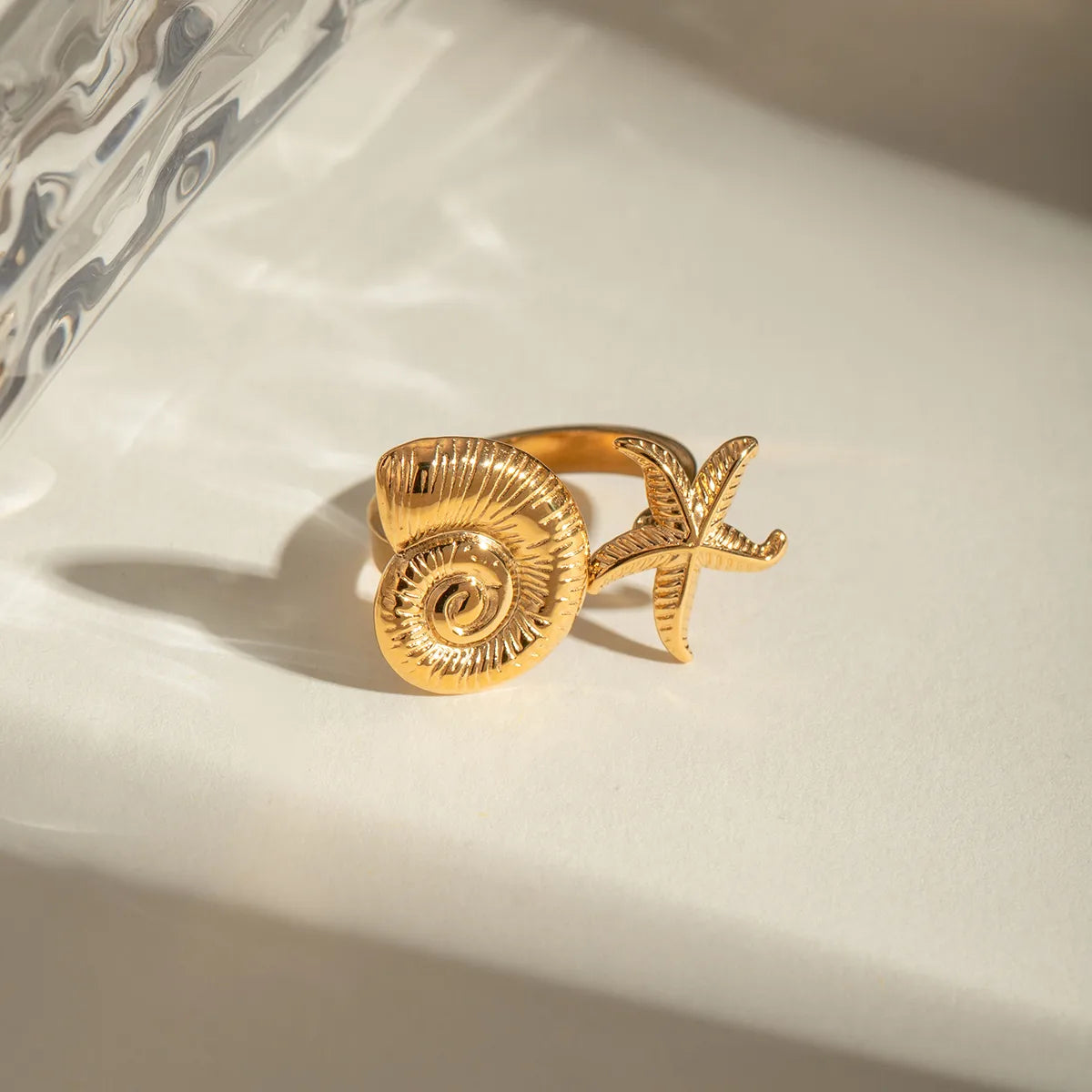 Ajoutez une touche marine et solaire à votre style avec cette bague ouverte dorée coquillage et étoile de mer. Son design inspiré des trésors de l’océan en fait un bijou unique, à la fois original et raffiné.