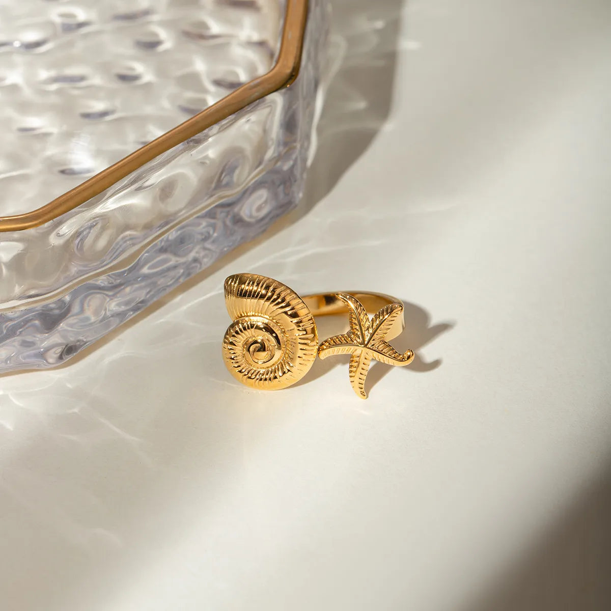 Ajoutez une touche marine et solaire à votre style avec cette bague ouverte dorée coquillage et étoile de mer. Son design inspiré des trésors de l’océan en fait un bijou unique, à la fois original et raffiné.