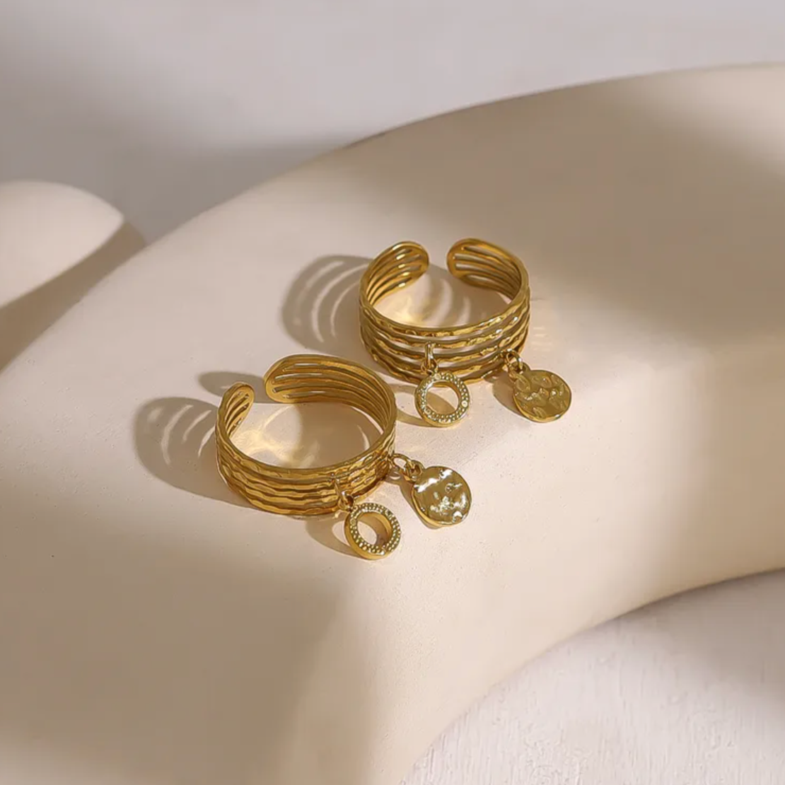 Bague dorée multi-rangs à l’allure bohème chic, ornée de deux breloques martelées qui ajoutent mouvement et éclat à votre main. L’alternance de lignes texturées donne un effet à la fois brut et raffiné, parfait pour un style affirmé et libre.

Réalisée en acier inoxydable avec un placage PVD or 18K, cette bague est résistante à l’eau, anti-ternissure et hypoallergénique. Un bijou fait pour durer, à porter au quotidien sans souci.

Matériaux : Acier inoxydable avec placage PVD or 18K, breloques texturées
Dim