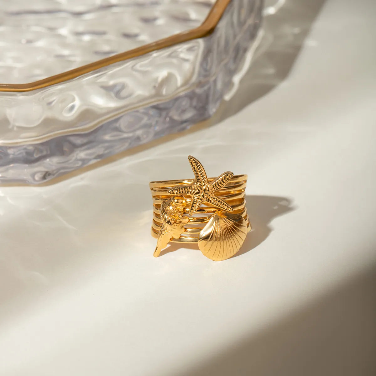 Ajoutez une touche marine et audacieuse à votre style avec cette bague dorée à l’or fin inspirée de l’univers marin. Ornée d’un trio de charms détaillés – une étoile de mer, un coquillage et un corail stylisé – elle incarne l’esprit des vacances avec élégance et originalité.