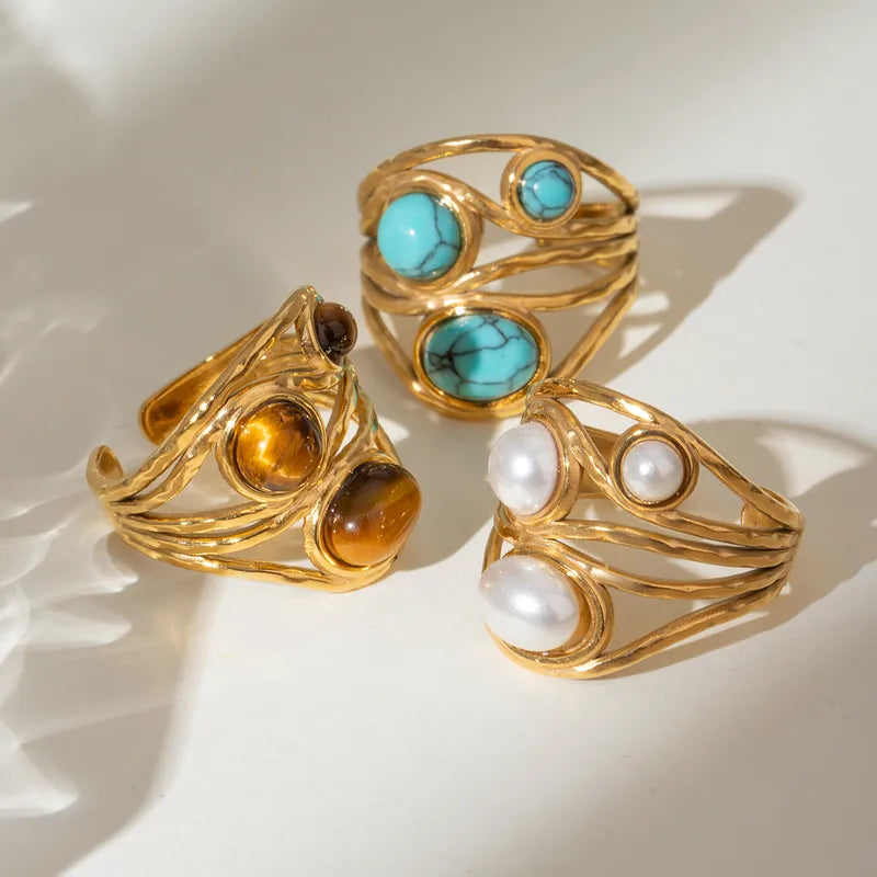 Ajoutez une touche de caractère et d’énergie à votre look avec cette bague en acier inoxydable doré ornée de trois perles en œil de tigre. Chaque pierre naturelle est unique, aux reflets chauds et profonds, sublimée par un design texturé aux lignes entrelacées.
