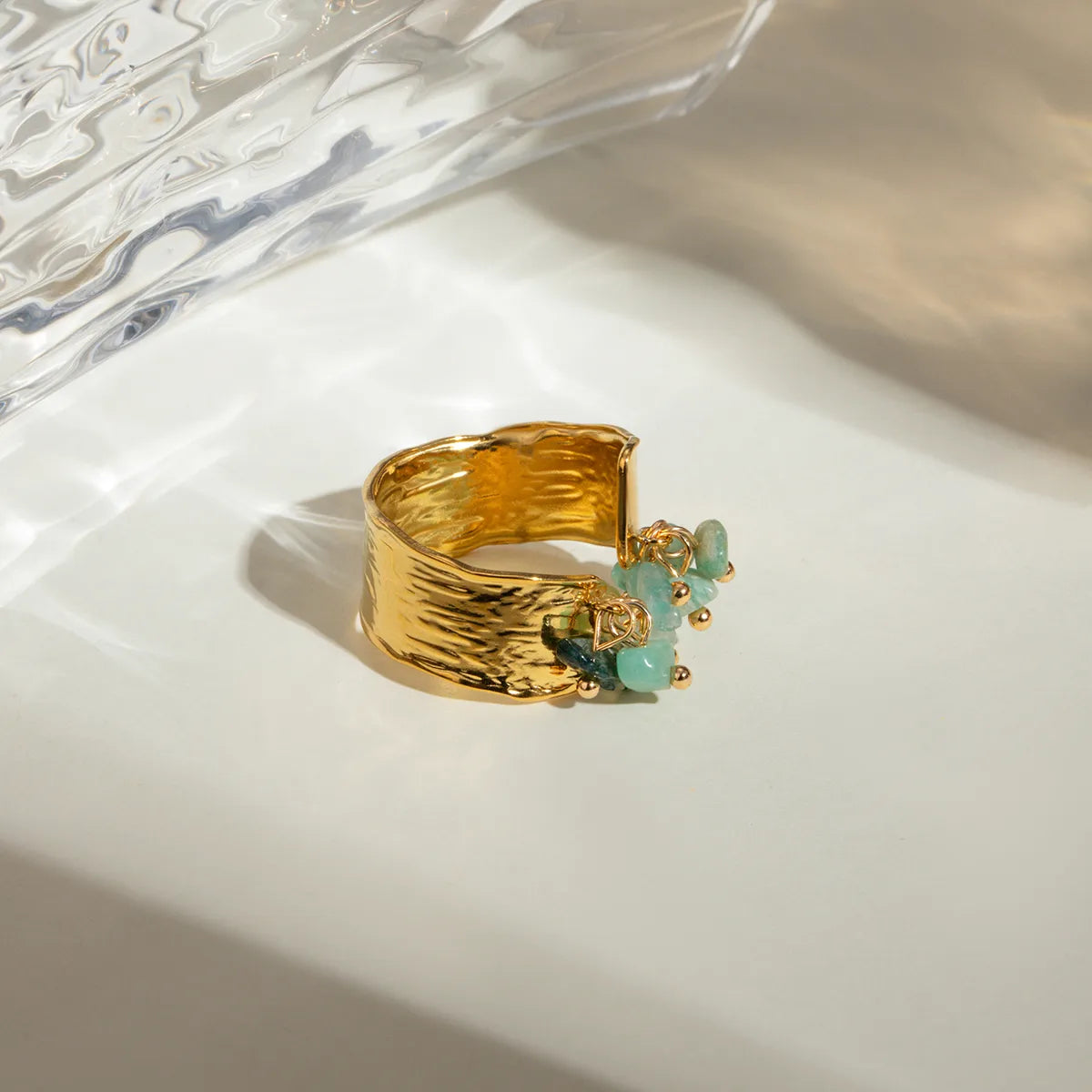 Ajoutez une touche de caractère et de fraîcheur à votre style avec cette bague ajustable en acier inoxydable doré ornée de pierres naturelles vert d’eau. Son design martelé associé à des pendentifs de pierres semi-précieuses crée un jeu de texture et de lumière unique, pour un bijou aussi audacieux qu’élégant.