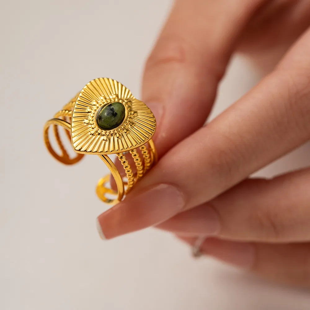Rayonnez avec cette bague en forme de cœur doré, finement gravée de rayons texturés autour d’un cabochon pierre verte. Ce bijou à l’allure solaire et protectrice mêle symbolisme spirituel et design affirmé, parfait pour révéler votre lumière intérieure.