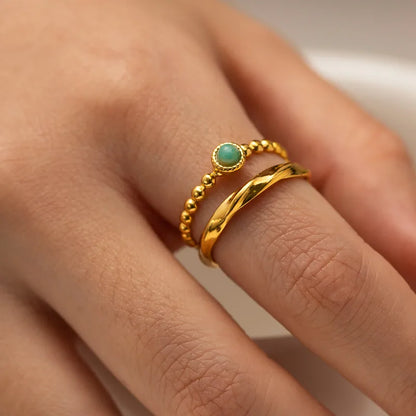 Offrez une touche de douceur minérale à votre main avec cette bague dorée en acier inoxydable, combinant un anneau perlé délicat et une bague torsadée lisse, unies par une pierre amazonite centrale aux reflets verts apaisants. Un bijou chic, fin et symbolique à la fois.