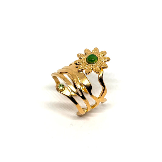 Bague dorée en acier inoxydable pour femme, au motif fleur solaire ornée d’une pierre verte lisse et d’un cristal facetté, au design organique et asymétrique, symbole de nature, d’énergie et de féminité créative.