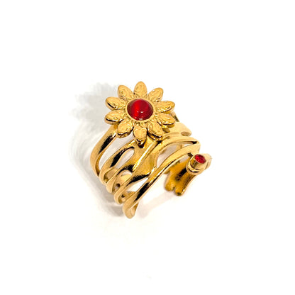 Bague dorée en acier inoxydable pour femme, ornée d’une fleur rayonnante inspirée du soleil avec pierre rouge centrale et petite pierre assortie, au style bohème, romantique et artistique, symbole de force et de féminité éclatante.