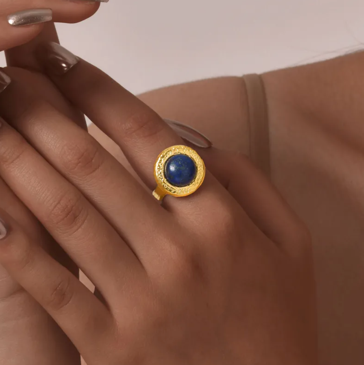 Élégante et puissante, cette bague associe une pierre bleue intense à une monture dorée martelée, pour un rendu inspiré des bijoux antiques.

Matériau : Acier inoxydable couleur doré, finition martelée. Pierre synthétique imitation lapis lazuli avec inclusions dorées.

Dimensions : Diamètre de la face : 1,68 cm. Taille ajustable. Poids : 6 g.

Design : Finition texturée et irrégulière évoquant l’artisanat ancien. La pierre bombée évoque un ciel étoilé, entre bleu nuit et reflets dorés.

Style : Parfait pour