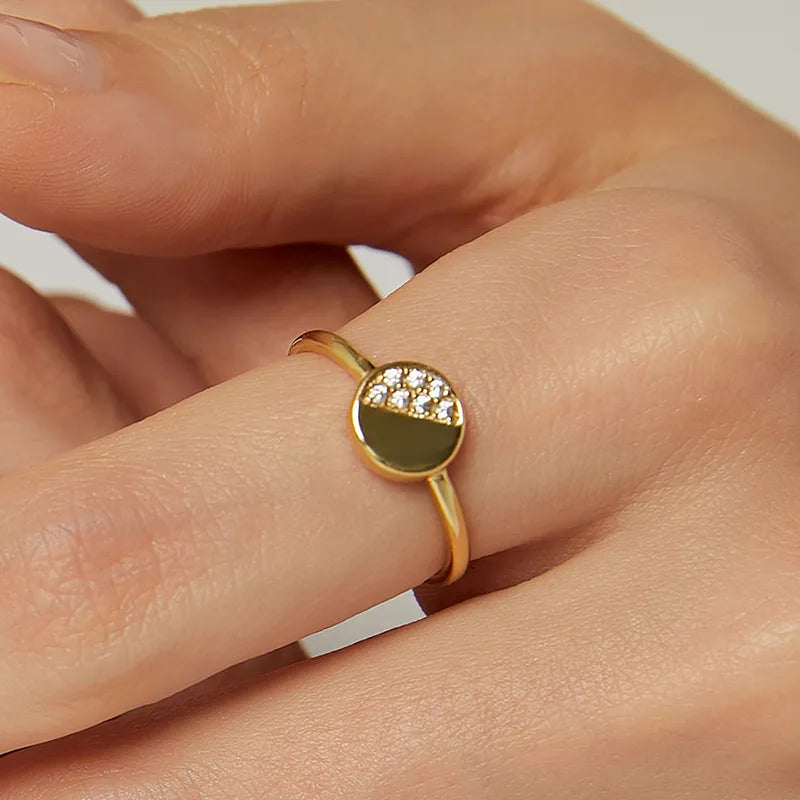 Bague dorée or 18K pour femme, au design géométrique minimaliste avec un cercle moitié doré moitié serti de zircons blancs, au style moderne et intemporel, parfaite pour un look chic et structuré.
