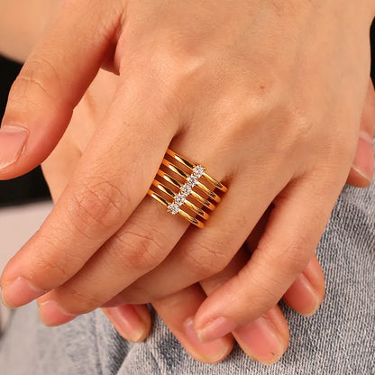 Bague dorée or 18K pour femme, composée de cinq anneaux parallèles traversés par une ligne de zircons scintillants, au design architectural et contemporain, parfaite pour un style audacieux, graphique et raffiné.