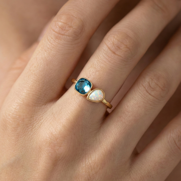 Bague dorée or 18k avec pierre bleue facettée et opale blanche, design asymétrique lumineux et élégant