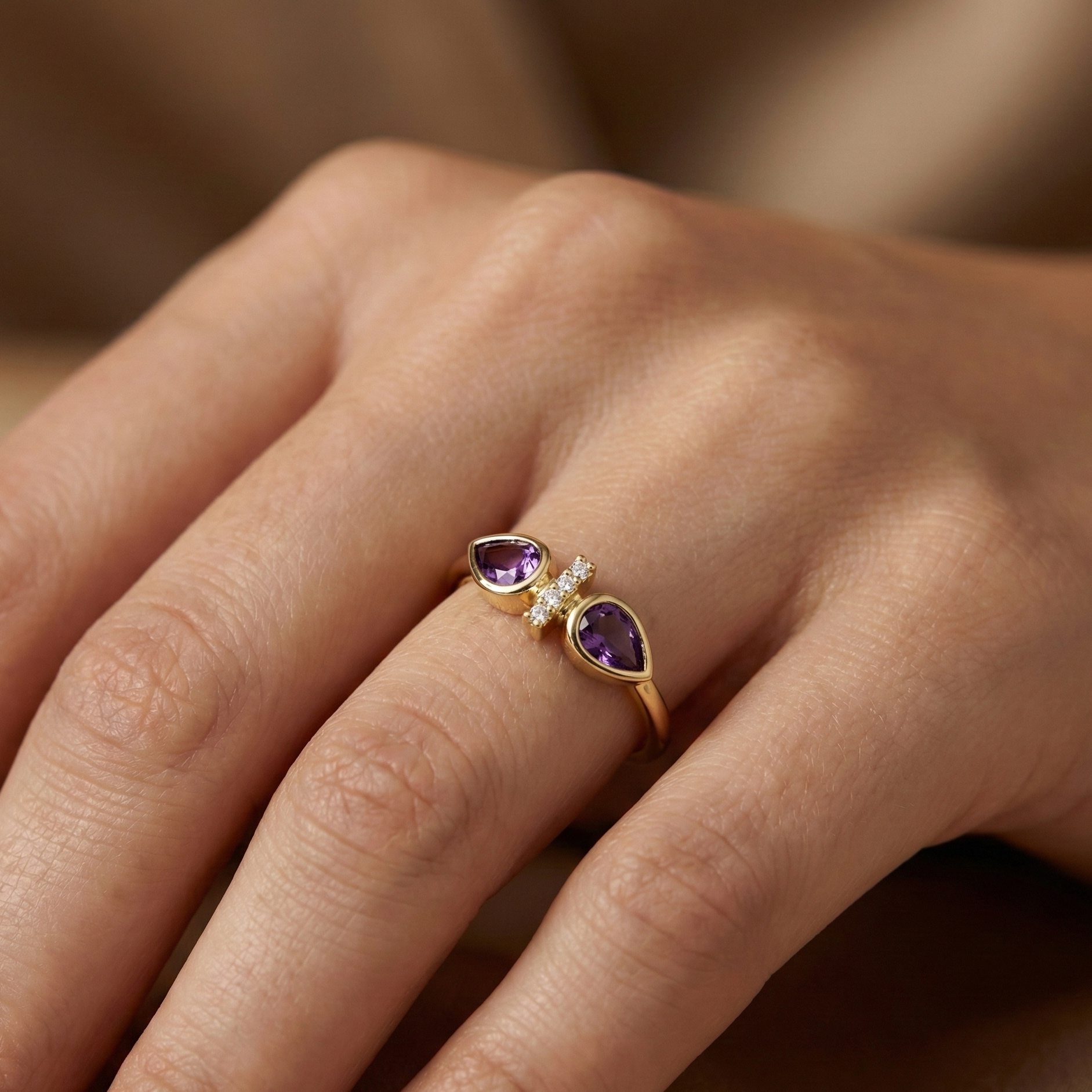 Bague dorée or 18k avec deux pierres violettes taille goutte et ligne de strass scintillants, design asymétrique élégant
