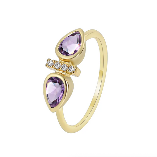 Bague dorée or 18K pour femme, ornée de deux pierres violettes en forme de goutte séparées par une ligne de zircons scintillants, au design ouvert asymétrique et raffiné, idéale pour un style romantique, coloré et sophistiqué.