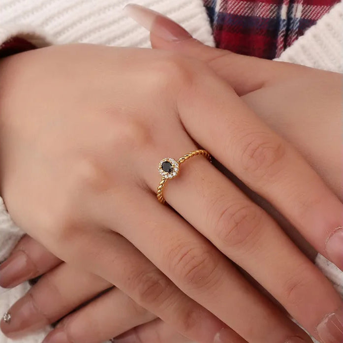 Bague dorée or 18K pour femme, ornée d’une pierre noire facettée entourée de zircons blancs sur un anneau torsadé raffiné, au style chic, féminin et intemporel, alliant contraste et élégance moderne.