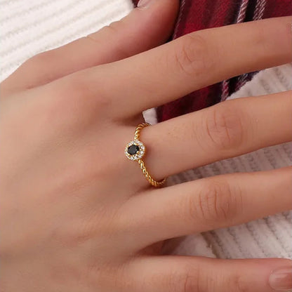 Bague dorée or 18K pour femme, ornée d’une pierre noire facettée entourée de zircons blancs sur un anneau torsadé raffiné, au style chic, féminin et intemporel, alliant contraste et élégance moderne.