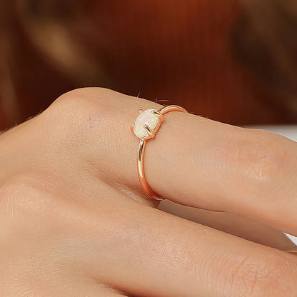 Bague dorée or 18K pour femme, ornée d’une pierre ovale effet opale aux reflets irisés, au style minimaliste et poétique, symbole de féminité et de lumière délicate.