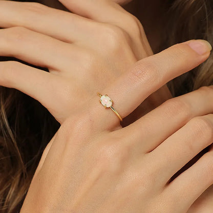 Bague dorée or 18K pour femme, ornée d’une pierre ovale effet opale aux reflets irisés, au style minimaliste et poétique, symbole de féminité et de lumière délicate.