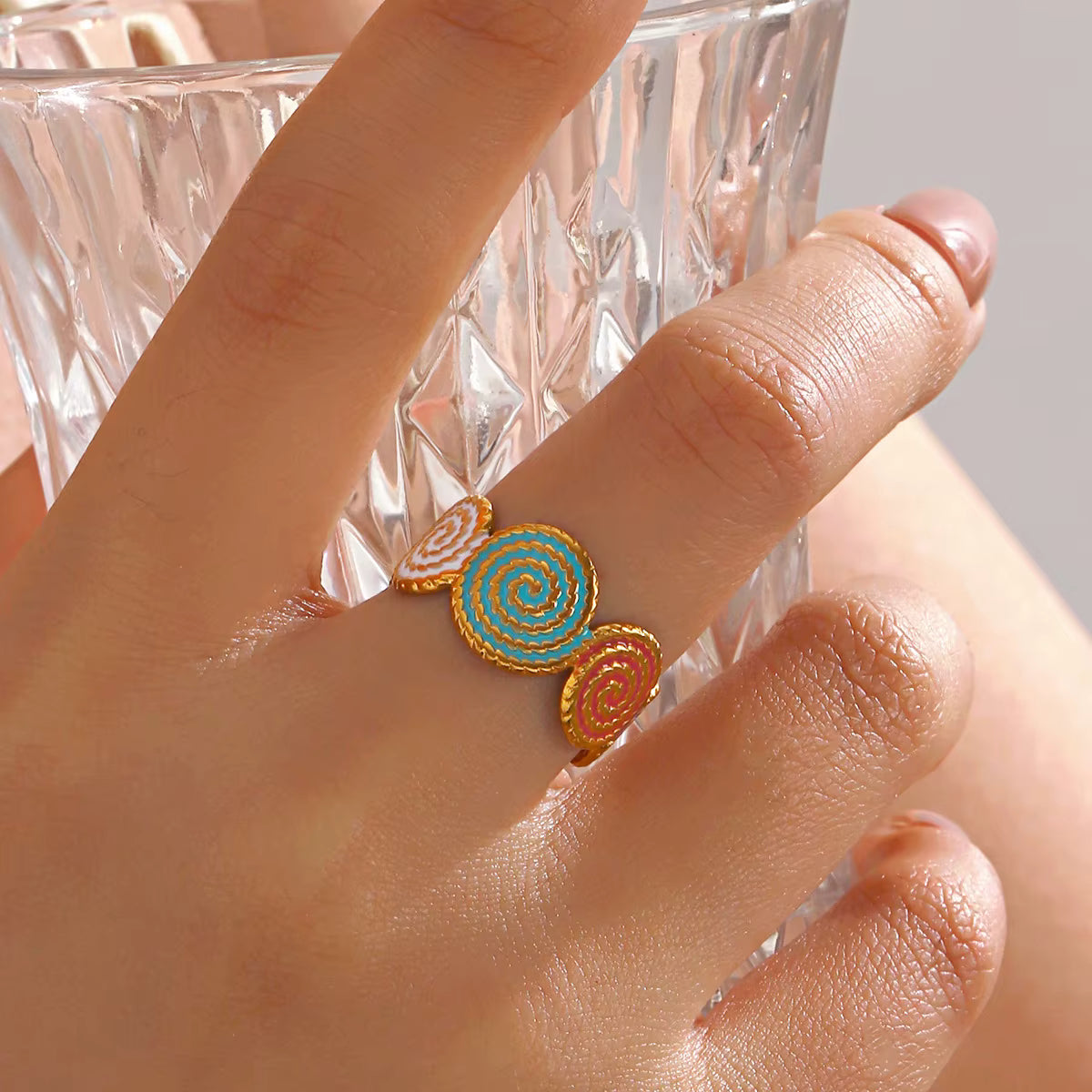 Bague dorée avec spirales colorées en émail turquoise et rouge, design artistique et moderne, bijou fantaisie lumineux.