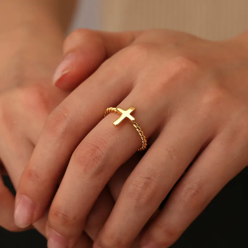 Bague femme dorée en or 18K avec croix horizontale lisse sur anneau torsadé. Bijou minimaliste et symbolique, raffiné et spirituel, parfait pour un look élégant et moderne