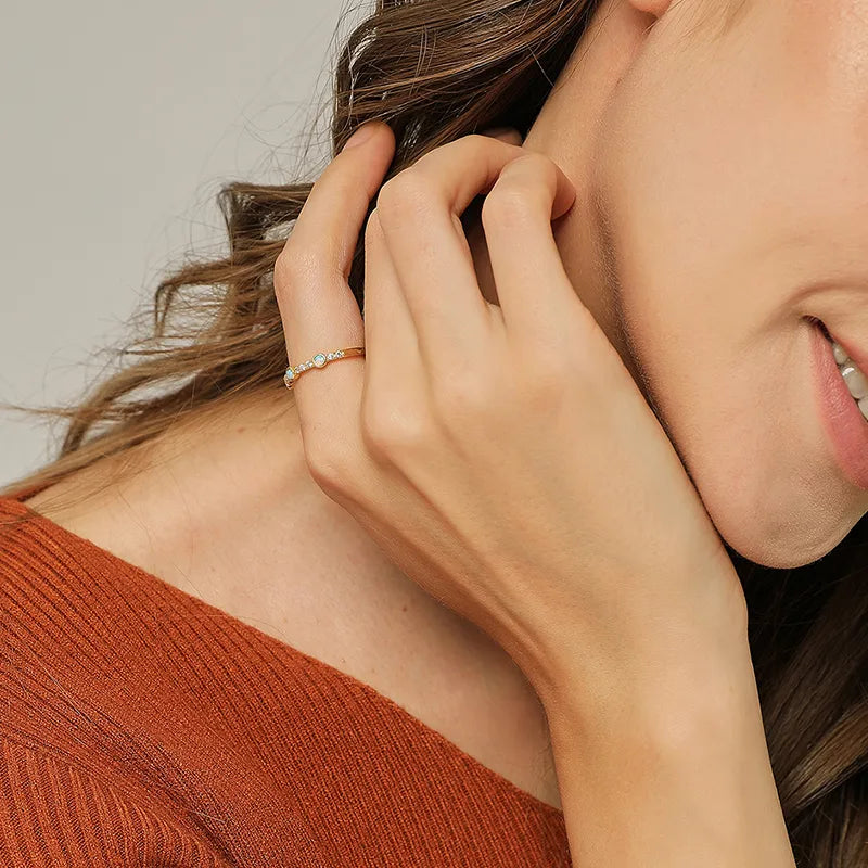 Bague femme dorée en or 18K, sertie de trois opales synthétiques irisées et de zircons blancs. Bijou raffiné au design fin et poétique, inspiré d’un halo céleste, idéal pour un look élégant et sophistiqué