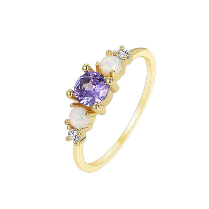 Cette bague féminine joue la carte du raffinement lumineux grâce à une composition délicate de pierres aux reflets changeants. Au centre, une pierre violette facettée attire tous les regards, accompagnée de deux opales blanches aux reflets irisés et de zircons scintillants de chaque côté. Un design équilibré, pensé pour capter la lumière et souligner la grâce de la main.