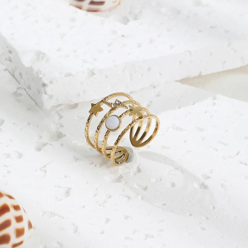 Ajoutez une touche céleste à votre style avec cette bague manchette dorée au design astral. Conçue en acier inoxydable doré, cette pièce unique arbore une étoile à 4 branches, un éclair incrusté de strass, un disque nacré et une étoile filante. L’ensemble repose sur une base martelée à plusieurs anneaux, apportant une texture raffinée et une structure moderne.