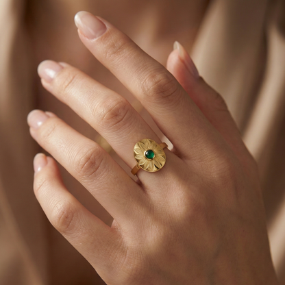 Bague manchette large en acier inoxydable doré, gravée de motifs feuilles avec une pierre verte centrale ovale.