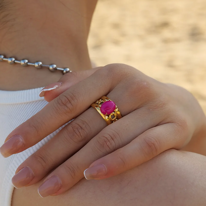 Affirmez votre style avec cette bague dorée ajourée, ornée d’un cabochon rose fuchsia éclatant. Son anneau travaillé de motifs baroques apporte relief et raffinement, tandis que la pierre centrale intensifie l’allure avec une touche glamour et assumée.