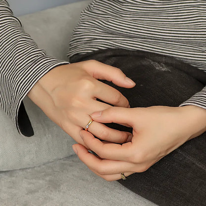 Bague plaqué or à anneau large et lisse, ornée d’une pierre marquise blanche sertie à plat, au design minimaliste et moderne pour un style chic et intemporel.