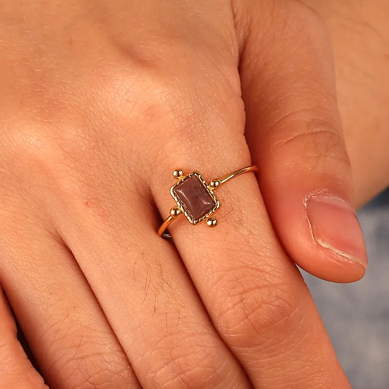 Bague plaqué or avec pierre rectangulaire prune foncé et quatre billes décoratives, au style antique et bohème chic, raffinée et pleine de caractère.