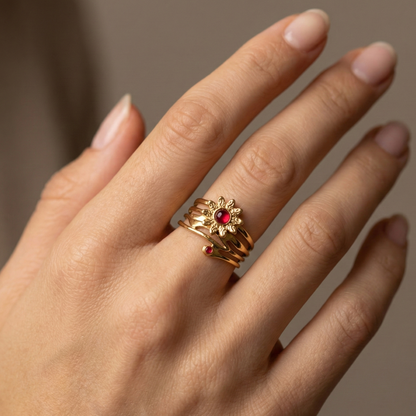 Bague solaire en acier inoxydable doré avec motif fleur rayonnante et pierres rouges, bijou symbolique et audacieux