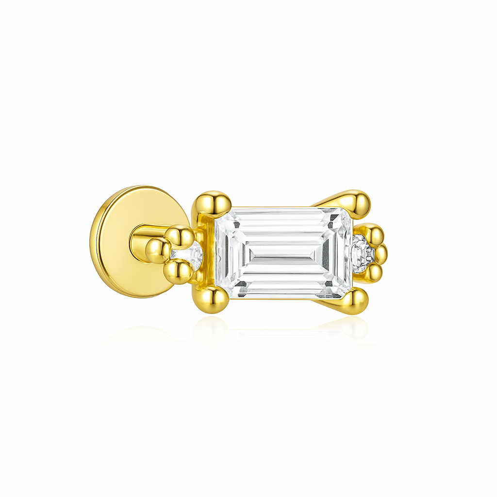 Élégante et structurée, cette boucle d’oreille clou associe un zircon taille émeraude rectangulaire à des motifs billes dorées de chaque côté. L’effet est à la fois architectural et féminin, entre rigueur des lignes et douceur des reliefs. Un bijou doré au style baroque revisité, très actuel.

Fabriquée en argent 925 doré à l’or fin, elle est hypoallergénique, résistante à l’eau, et pensée pour une tenue parfaite au quotidien.

Matériaux : Argent 925 doré à l’or fin, zircon rectangulaire, détails billes
Typ