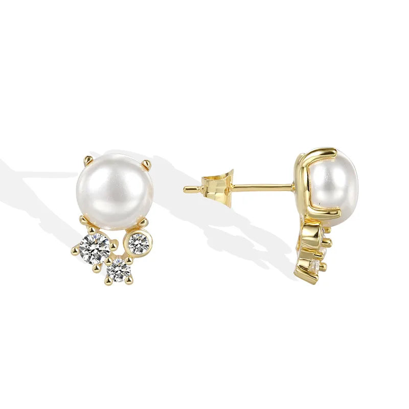 Boucles d’oreilles clous dorées pour femme en plaqué or, ornées d’une perle blanche synthétique et de trois zircons étincelants. Bijou élégant et raffiné, au style classique revisité, parfait pour sublimer le visage avec éclat et douceur