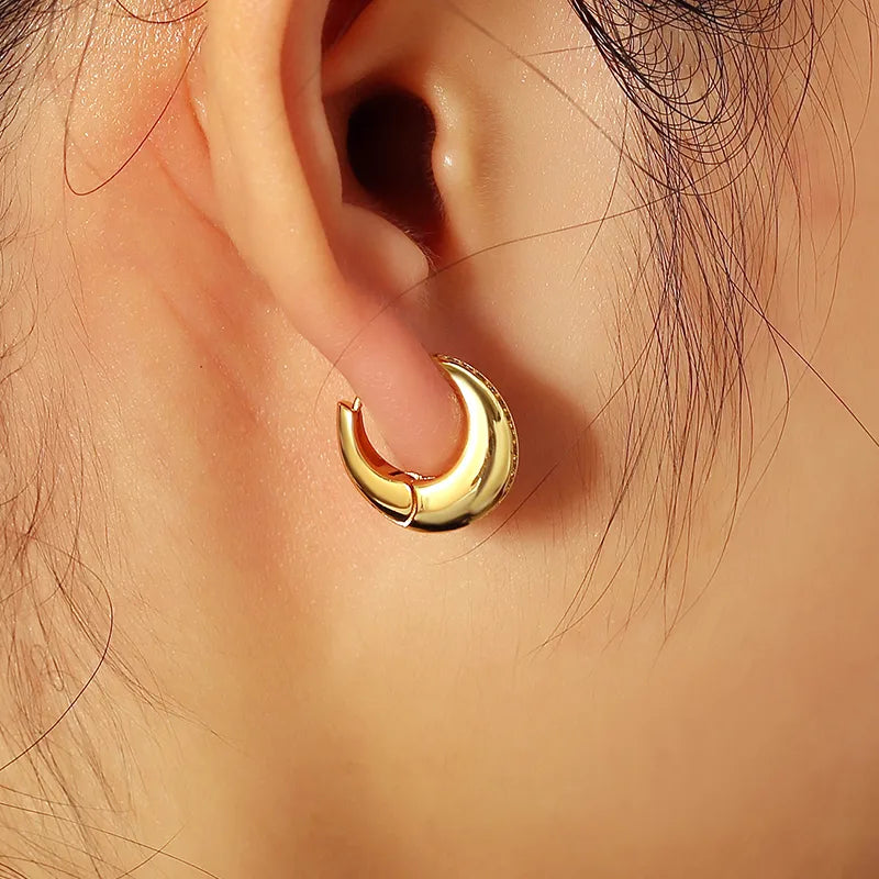 Boucles d’oreilles créoles bombées dorées pour femme en plaqué or, ornées d’une ligne de strass délicats sur une face. Bijou chic et moderne au design sculptural et brillant, idéal pour un look élégant, urbain et raffiné