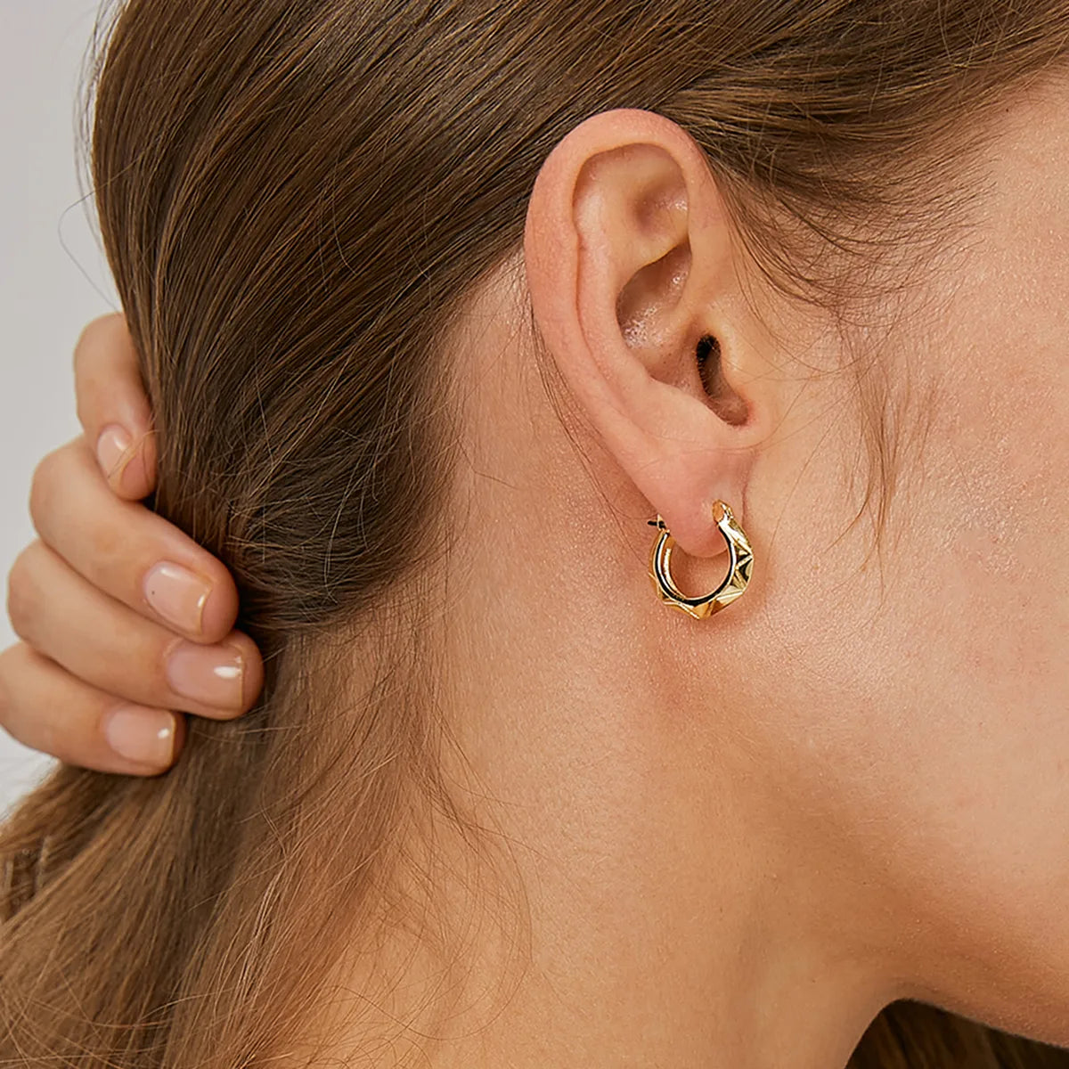 Boucles d’oreilles créoles dorées pour femme en plaqué or, au design géométrique facetté et angulaire. Bijou moderne et architectural au style minimaliste et raffiné, léger et confortable, parfait pour une allure urbaine et contemporaine