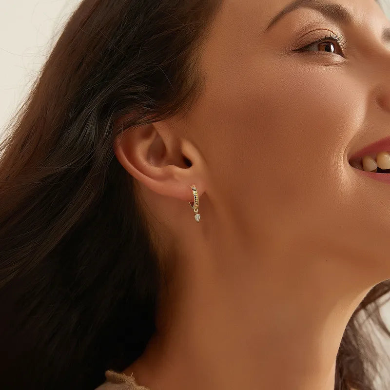 Boucles d’oreilles créoles dorées pour femme en plaqué or, ornées d’une pampille en zircon taillée en goutte d’eau. Bijou délicat et lumineux au design texturé et raffiné, parfait pour une allure moderne, féminine et élégante