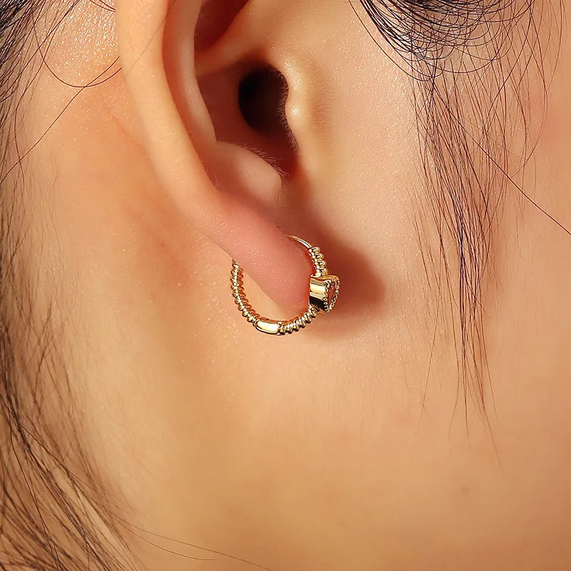 Boucles d’oreilles créoles dorées pour femme en plaqué or, ornées d’une pierre rose en forme de cœur sertie sur une monture torsadée texturée. Bijou romantique et moderne, lumineux et raffiné, symbole de tendresse et de féminité