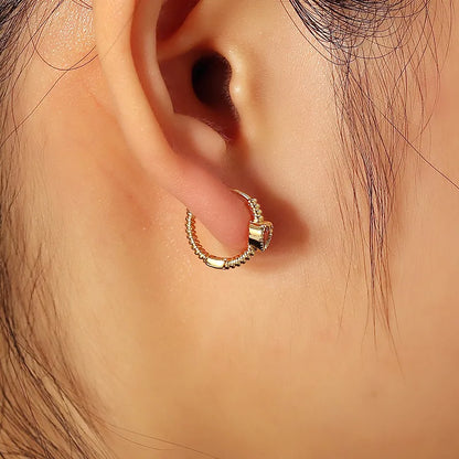 Boucles d’oreilles créoles dorées pour femme en plaqué or, ornées d’une pierre rose en forme de cœur sertie sur une monture torsadée texturée. Bijou romantique et moderne, lumineux et raffiné, symbole de tendresse et de féminité