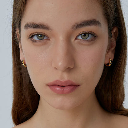 Boucles d’oreilles créoles dorées pour femme en plaqué or, serties de pierres noires au design irrégulier. Bijou moderne et contrasté au style urbain chic, alliant éclat doré et profondeur mystérieuse, parfait pour un look affirmé et élégant