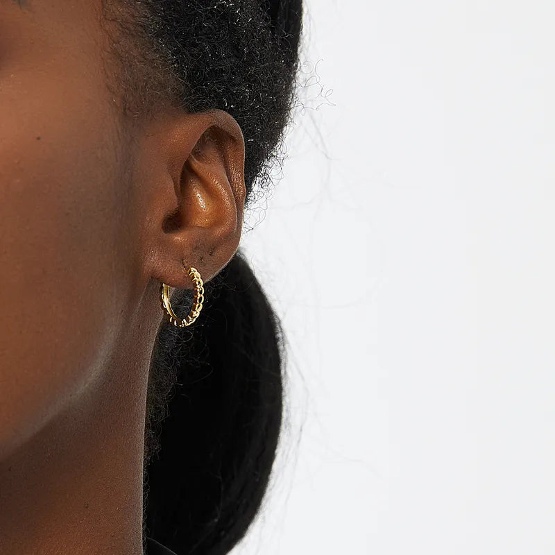 Boucles d’oreilles créoles dorées pour femme en plaqué or, au design texturé effet perlé. Bijou chic et moderne, lumineux et raffiné, parfait pour un look casual chic ou une tenue élégante au quotidien