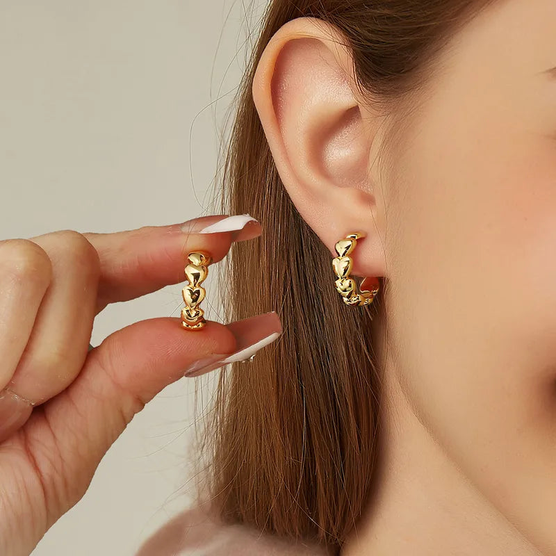 Boucles d’oreilles créoles dorées pour femme en plaqué or, en forme de cœurs bombés successifs au fini poli brillant. Bijou romantique et tendance au style féminin et lumineux, parfait pour un look élégant ou un cadeau symbolique